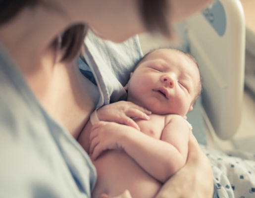Mother holding newborn baby in hospital bed