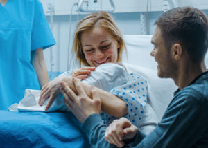 Smiling parents holding newborn in hospital after delivery